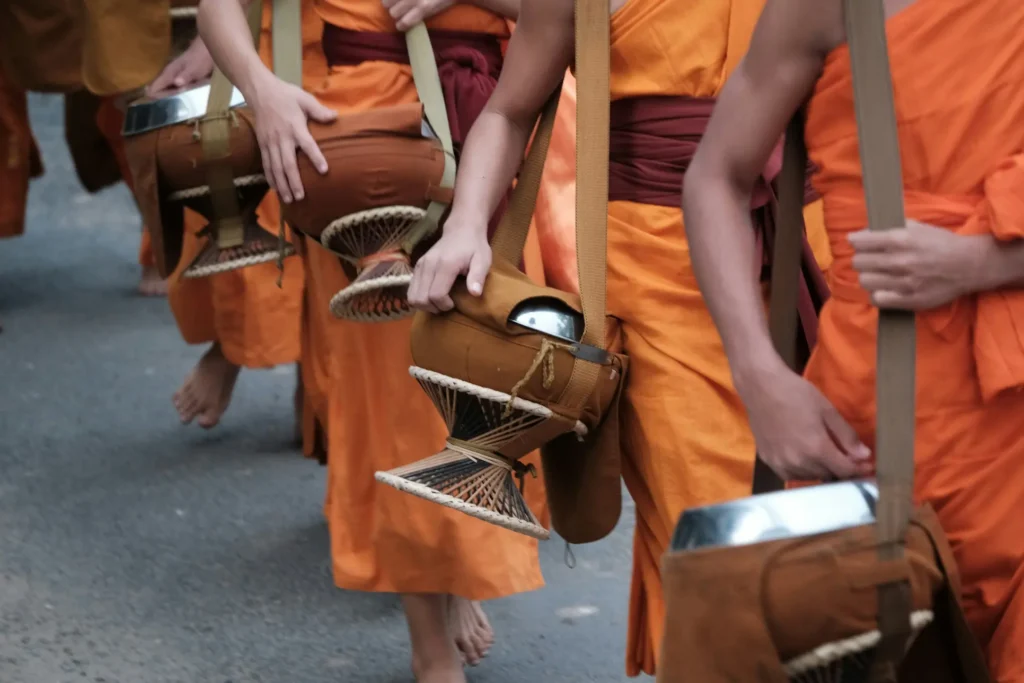 Buddhist monks in saffron robes collecting alms at sunrise in Luang Prabang
